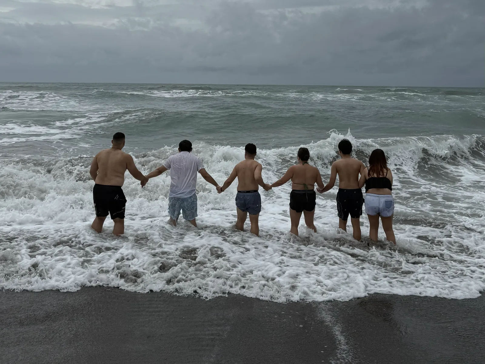 OCPC members holding hands while wading into strong waves in La Union